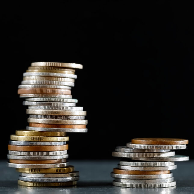 Stock photo of two piles of coins. First pile is taller than the second.