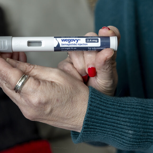 Close up of an older woman's hands holding a WeGovy semaglutide injection pen