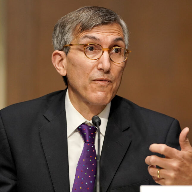 FDA official Peter Marks, wearing glasses and a purple tie, talks and gesturing one hand -- coverage from STAT