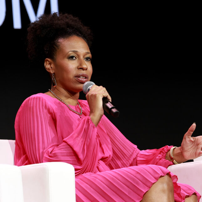 Aletha Maybank holds a microphone while speaking on stage, sitting in a couch -- coverage from STAT