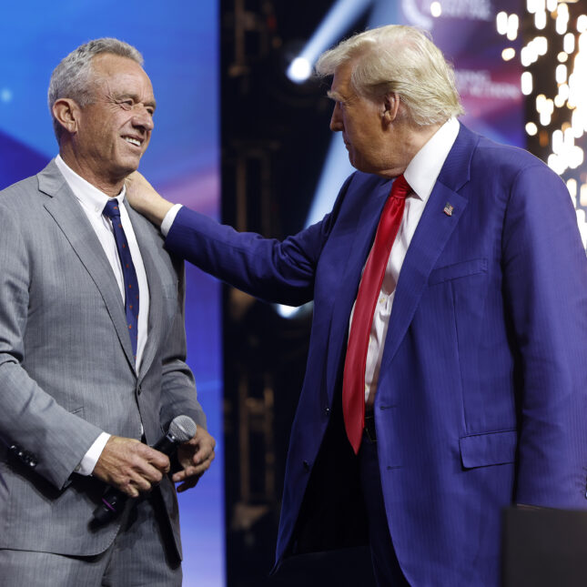 Former U.S. President Donald Trump, on the left side, taps Robert F. Kennedy Jr.'s shoulder as Kennedy Jr. smiles on stage -- first opinion coverage from STAT