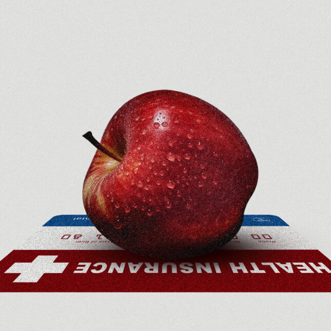 An apple lays on top of a health insurance card -- insurance coverage from STAT